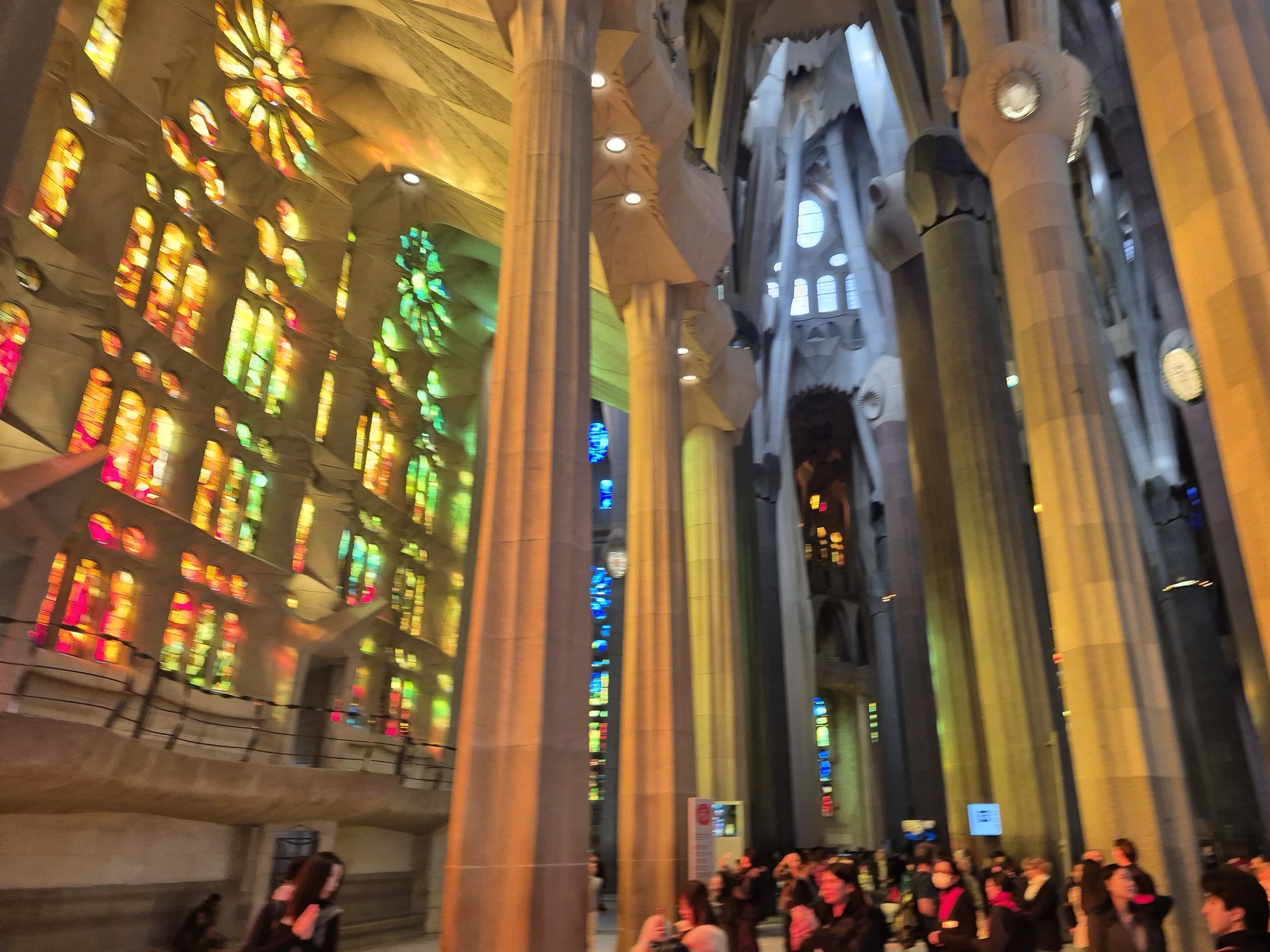 The interior of the Sagrada Família in Barcelona, tree-like columns and stained glass flooding the nave with coloured light
