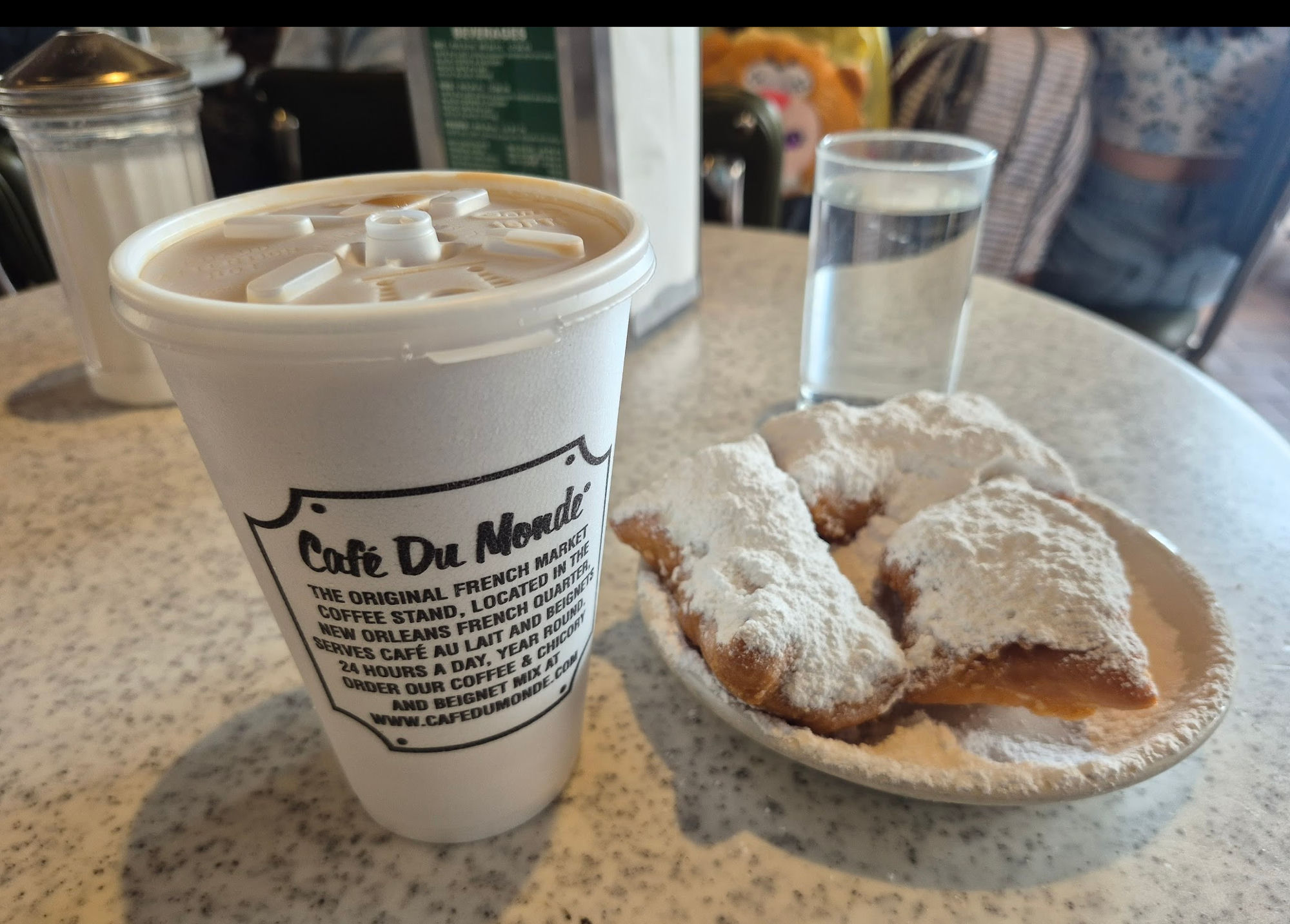 A plate of beignets dusted with powdered sugar and a café au lait at Café du Monde, New Orleans
