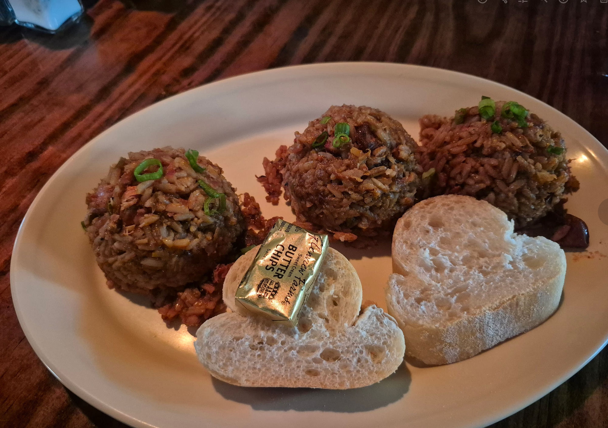 Three scoops of New Orleans jambalaya — rice cooked with meat — served with crusty bread and a pat of butter